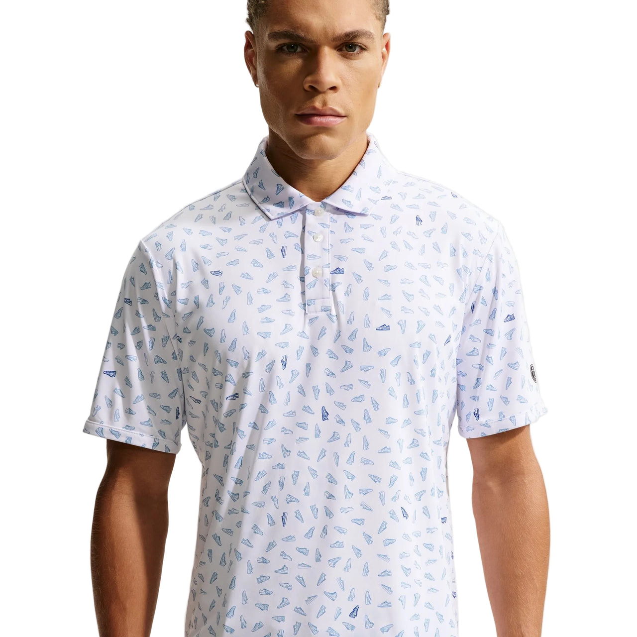 Man wearing a white polo shirt with blue pattern against a plain background