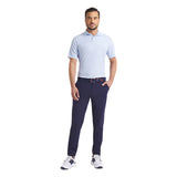 Man wearing a light blue checkered polo shirt and navy pants on a white background