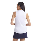 Woman wearing a white sleeveless top and navy skirt on a light gray background